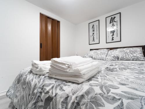 a bed with a pile of white pillows on it at Cozy Private 2 bedroom apartment, free Wifi, free parking in heart of Toronto, surrounded by nature in Toronto