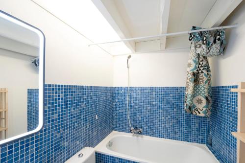 a blue tiled bathroom with a tub and a shower at Superbe Appartement Vue Océan in Capbreton