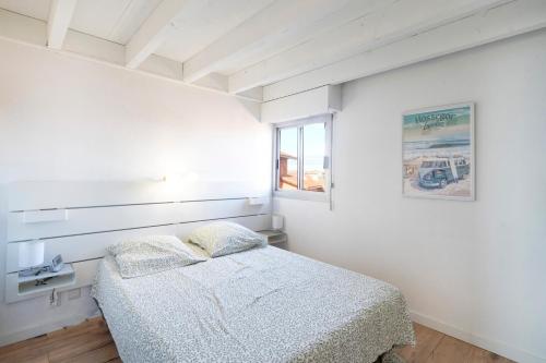 a white bedroom with a bed and a window at Superbe Appartement Vue Océan in Capbreton