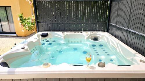 eine Badewanne mit einem Glas Wein darin in der Unterkunft Appartement de standing avec jacuzzi in Le Val