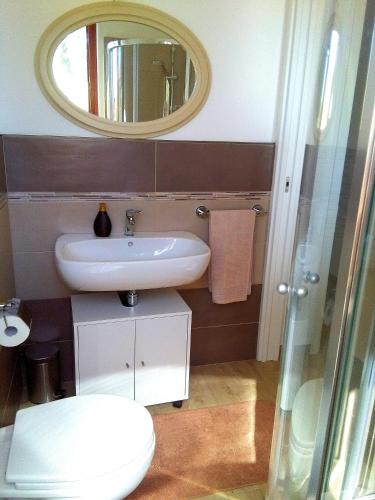 a bathroom with a sink and a mirror and a toilet at La Casetta Holiday Home in Alghero