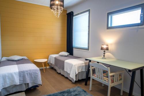 una stanza con due letti, un tavolo e una scrivania di Aurinkorinne 8 a Kalajoki