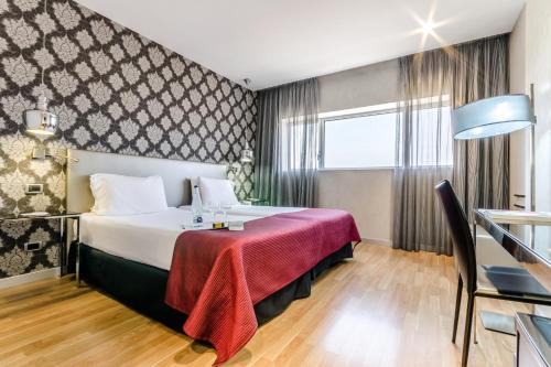 Habitación de hotel con cama con manta roja en Eurostars Executive, en Barberà del Vallès