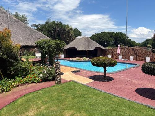 una piscina en un patio con techo de paja en Remi's B & B and SPA, en Pretoria