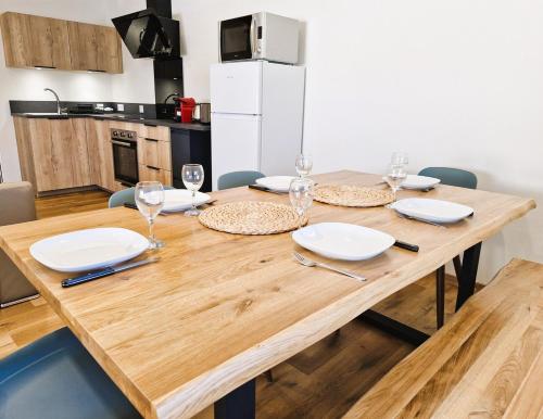 ein Holztisch mit Tellern und Weingläsern darauf in der Unterkunft Appartement 3 chambres in Montceau-les-Mines
