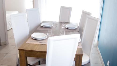 a dining room table with white plates and chairs at Résidence Thalacap in Cap d'Agde
