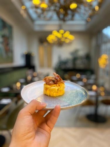 una persona sosteniendo un plato con un pedazo de comida en él en Hotel Damier Kortrijk, en Cortrique