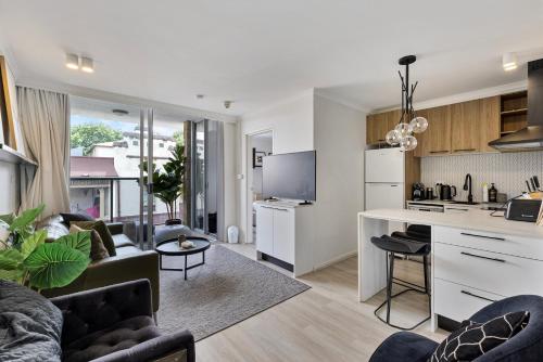 a kitchen and living room with a couch and a table at Stylish 1-Bedroom Stay with Balcony & Amenities in Sydney