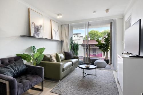 a living room with a couch and a tv at Stylish 1-Bedroom Stay with Balcony & Amenities in Sydney