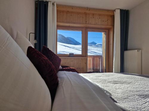 ein Schlafzimmer mit einem Bett und Blick auf den Schnee in der Unterkunft Neunerköpfle in Tannheim