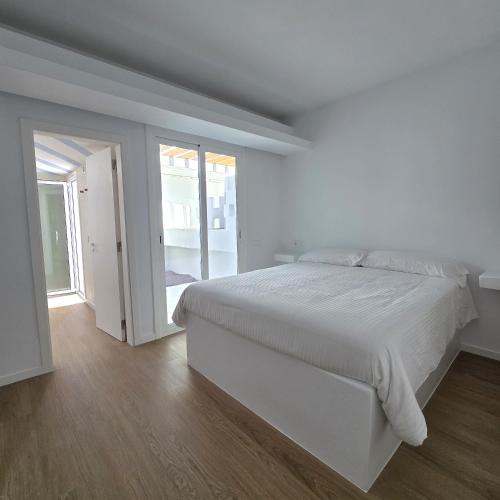 a white bedroom with a bed and a sliding glass door at Bungalows Villas Blancas in Puerto del Carmen