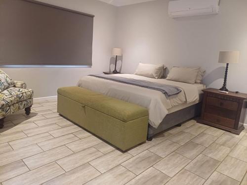 a bedroom with a bed and a couch and a chair at Carshalton Cottage in Mooirivier