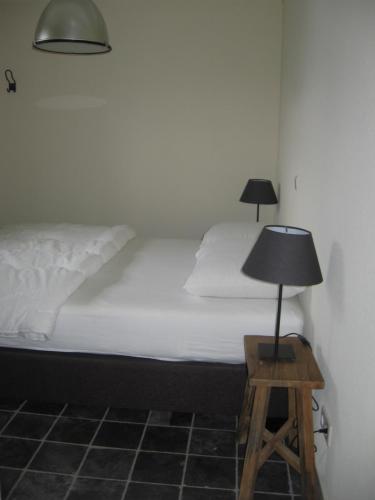 1 dormitorio con 1 cama con lámpara en un taburete en De Zandkant, en Biezenmortel