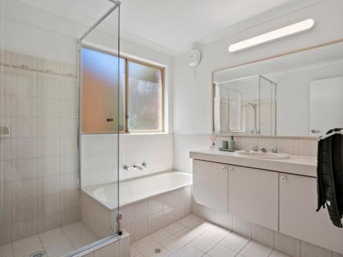 a bathroom with a shower and a tub and a sink at Ocean Reef Marina by the Sea 4BR plus Study plus in Perth
