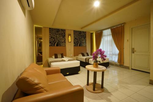a living room with two beds and a couch and a table at Hotel Grand Rosela in Yogyakarta
