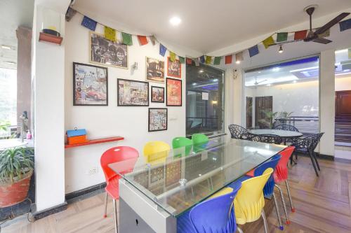 Un comedor con sillas de colores y un mostrador de cristal. en FabHotel Pooja Residency, en Gurgaon