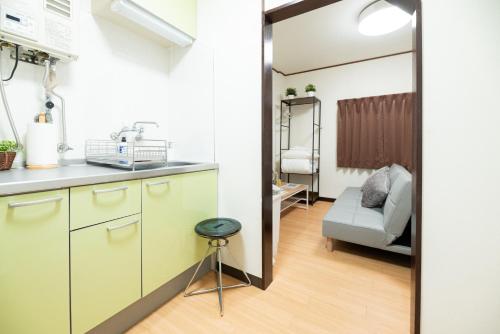 a kitchen with a sink and a couch in a room at マエカワビル403Private In-Room Theater in Osaka