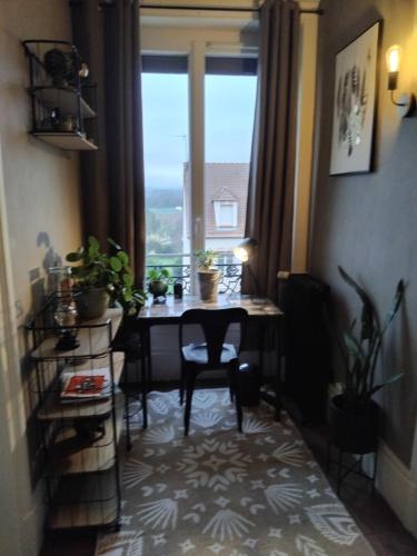 a room with a table and a window with plants at L'appart in Vinneuf