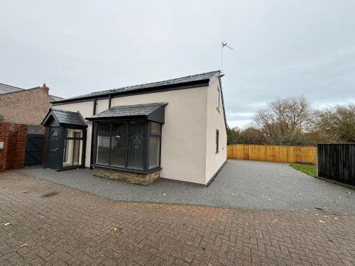 ein weißes Gebäude mit schwarzen Fenstern und einem Zaun in der Unterkunft Rose Cottage by Sasco in Blackpool