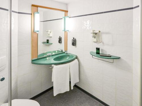 baño con lavabo verde y espejo en Ibis Valladolid, en Valladolid
