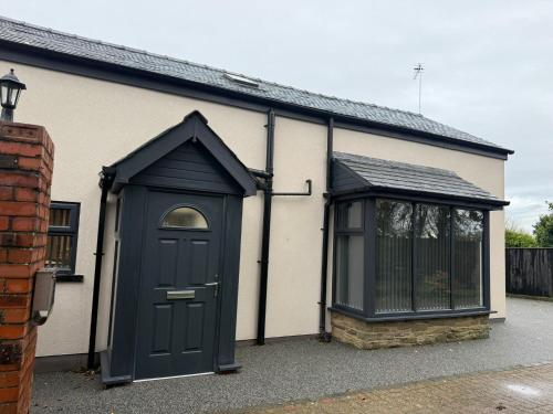 ein Haus mit einer schwarzen Tür und einem Fenster in der Unterkunft Rose Cottage by Sasco in Blackpool