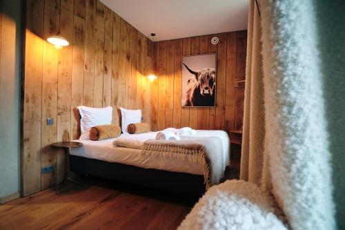 a bedroom with a bed with a picture of a cow on the wall at Les Suites de Petit Bomal in Durbuy