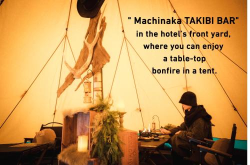 Eine Frau, die an einem Tisch in einem Raum mit einem Schild sitzt. in der Unterkunft Cross Hotel Sapporo in Sapporo