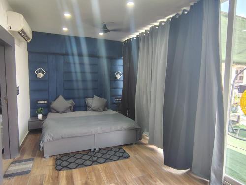 a bedroom with a bed with blue walls and wooden floors at Rusha Stays in Gumgaon