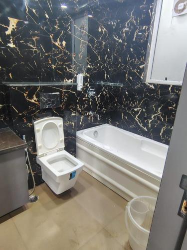 a bathroom with a toilet and a tub and a sink at Rusha Stays in Gumgaon