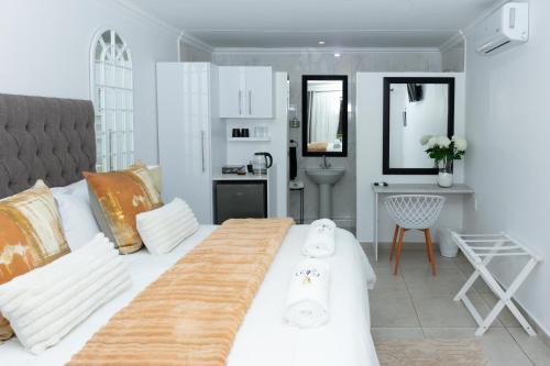 ein Schlafzimmer mit einem großen weißen Bett und ein Badezimmer in der Unterkunft Relmies Place in Modimolle