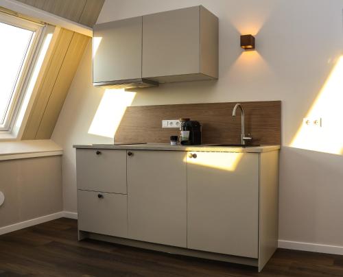 Zicht op Urk في أورك: مطبخ بخزائن بيضاء ومغسلة