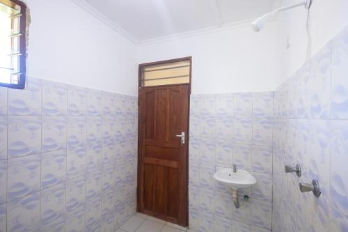 a bathroom with a wooden door and a sink at Kash apartments in Diani Beach