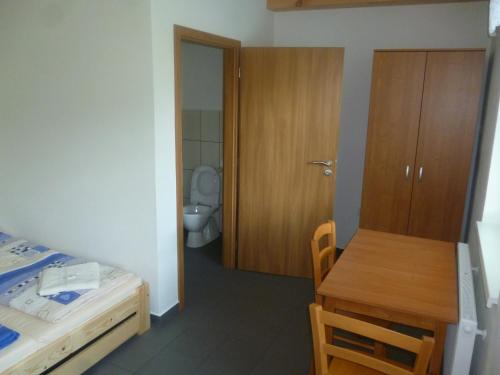 a bedroom with a bed and a table and a toilet at Penzion Na Podlesí ve Zlaté Koruně in Zlatá Koruna