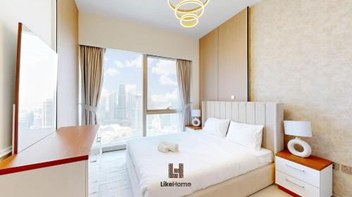 Un dormitorio con una cama blanca con una ventana grande. en Wake Up to Burj Khalifa Views Next to Dubai Mall Luxury 2BR Downtown Like Home, en Dubái