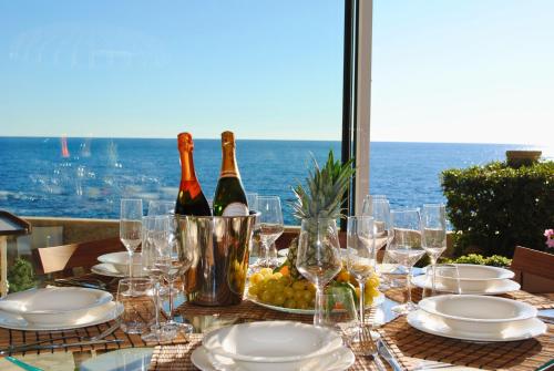 Villa Capdale Horizon with separate guest house في كاب دايل: طاولة عليها زجاجات نبيذ وأطباق وكؤوس