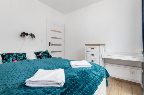 米泽德沃兹Little Laguna Apartments SPA & Gym by Noclegi Renters的卧室里有一张蓝色的床，床上放着毛巾