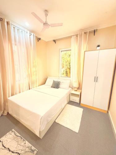 a bedroom with a large white bed and a window at Blesauz Apartments in Dar es Salaam
