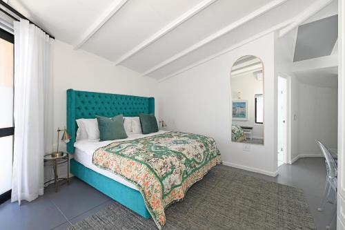 a bedroom with a blue bed with a green headboard at No. 6 The Yard in Franschhoek