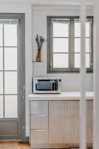 a microwave on a counter in a kitchen with windows at Maison de Pêcheur - La Coquette in Trouville-sur-Mer
