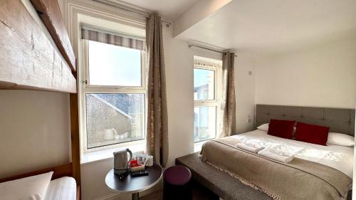 a small bedroom with a bed and two windows at Reef Lodge in Newquay