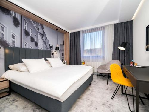 ein Hotelzimmer mit einem großen Bett und einem Schreibtisch in der Unterkunft Mercure Jelenia Góra in Jelenia Góra
