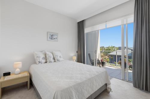 Sea Salt - Peppers Balé 1BR Apartment by uHoliday في كينغسكليف: غرفة نوم بيضاء مع سرير وشرفة