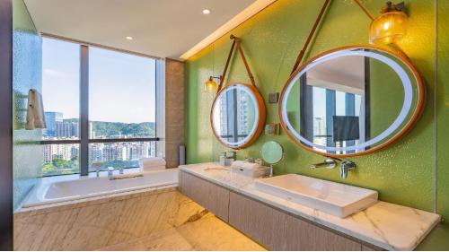 ein Badezimmer mit zwei Spiegeln, einer Badewanne und einem Waschbecken in der Unterkunft Holiday Inn Zhuhai City Center by IHG in Zhuhai