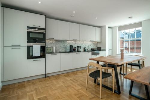 a kitchen with white cabinets and a wooden table at Stunning flat near Holland Park in London