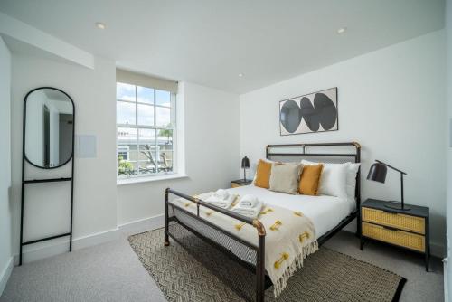 a white bedroom with a bed and a mirror at Stunning flat near Holland Park in London