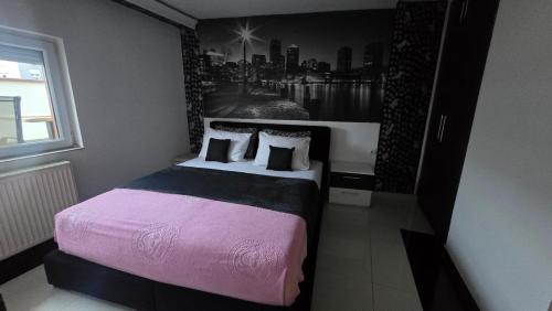 a bedroom with a large bed with a picture of a city at Tvrdjava Apartman in Petrovaradin