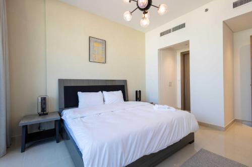 a bedroom with a large white bed and a table at Chic & Bright 1BR Lagoon Suite in Gateway II in Ras al Khaimah