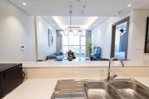 a kitchen with a sink and a living room at Chic & Bright 1BR Lagoon Suite in Gateway II in Ras al Khaimah