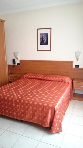 a bedroom with a bed with a orange comforter at Hotel Holiday House in San Giovanni Rotondo