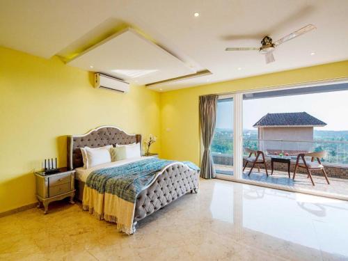 a bedroom with a bed and a balcony with a table at The Infinity Pool Villa Hotel by DanCenter, Baga Beach, Goa in Arpora